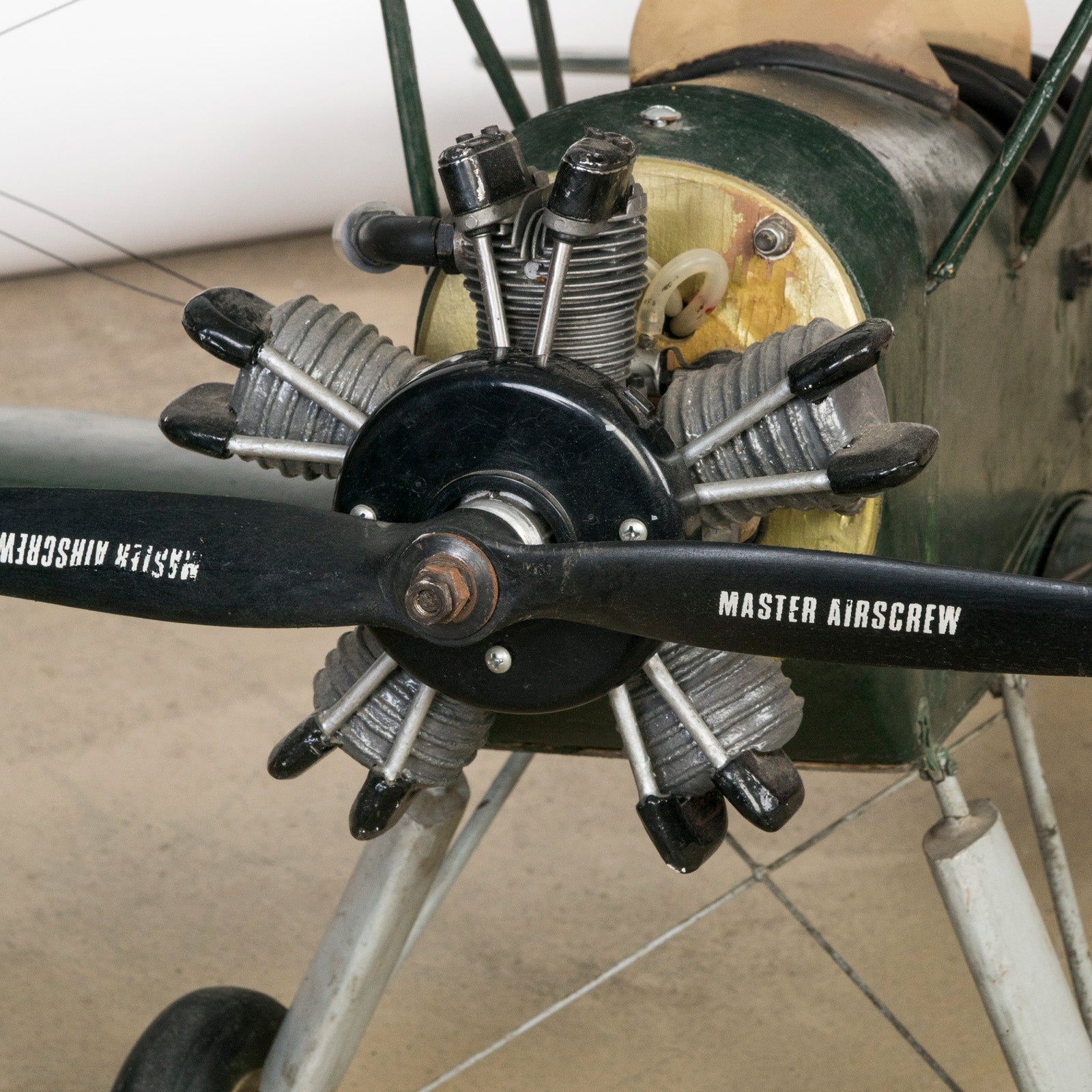 Close-up of the engine of a dark green vintage biplane model—a finely crafted 1970s replica of the 1954 Ha-Pao aircraft—featuring bold red and white striped wings. Available at Wildschut Antiques.