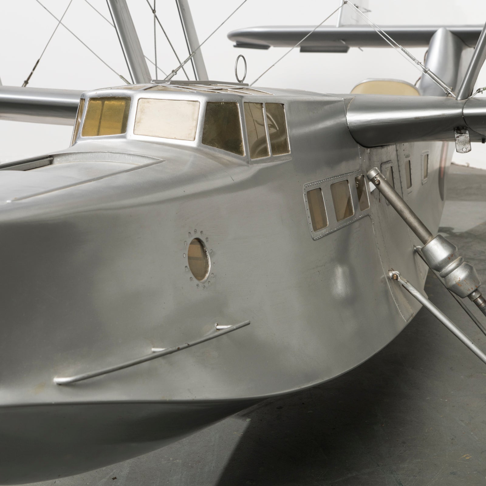 Close-up of the cockpit of a large vintage model of a World War I-era airplane with a silver finish