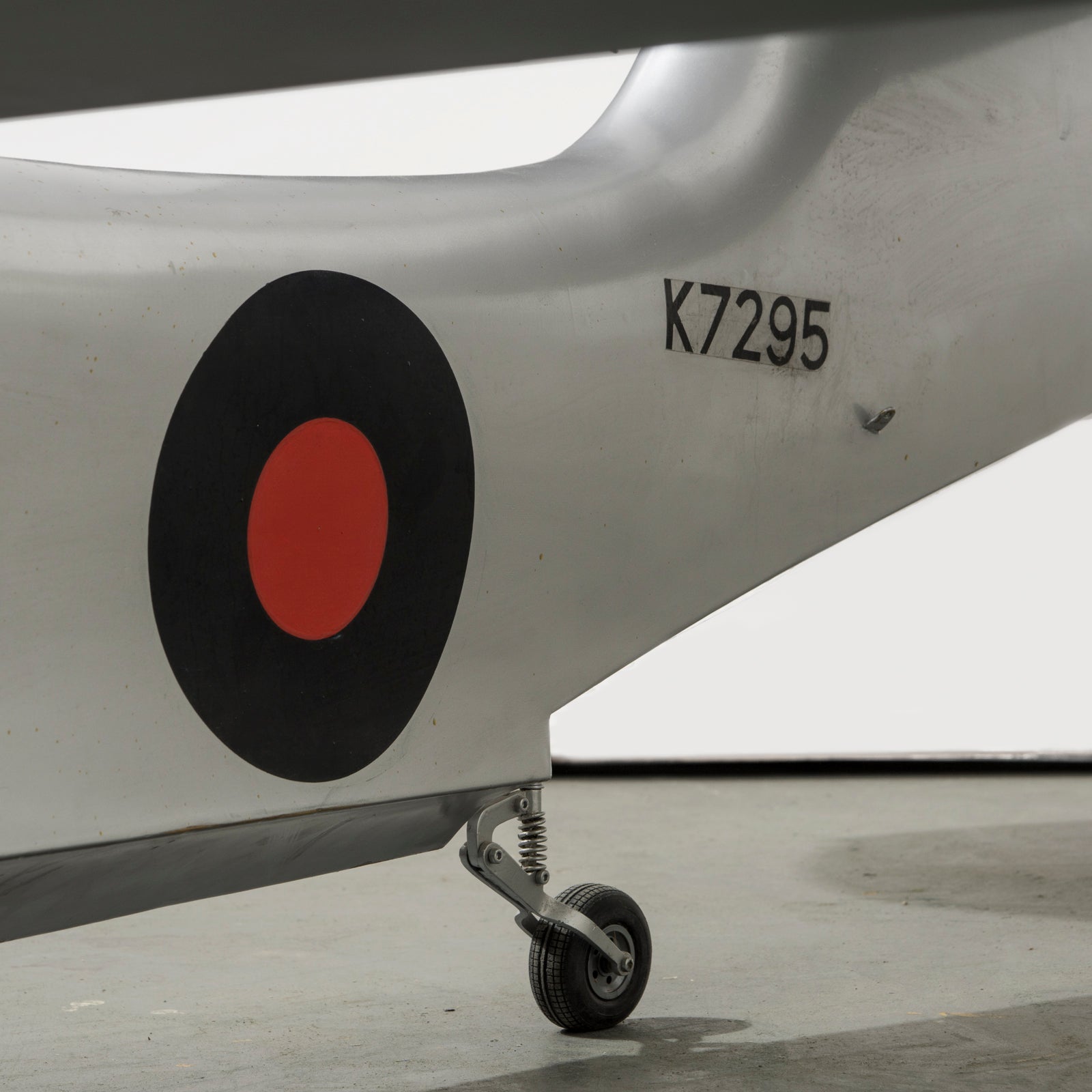 Close-up of a large vintage model of a World War I-era airplane with a silver finish, black and red detailing