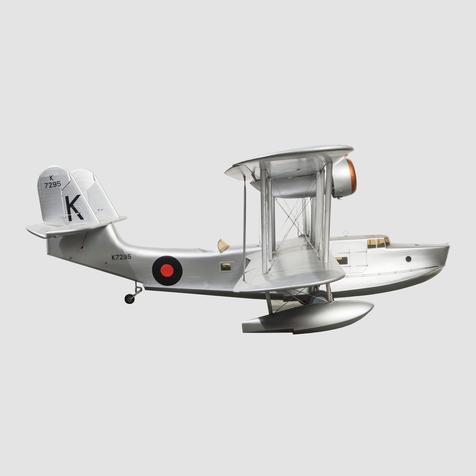 Sideview of a large vintage model of a World War I-era airplane with a silver finish, black and red detailing, and a large 'K' on the wing, available at Wildschut Antiques