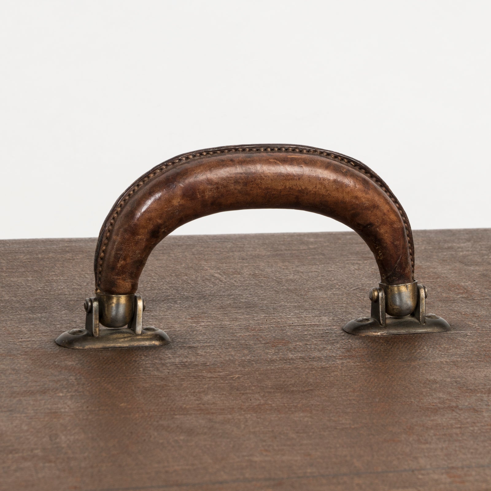 Close-up of the leather handle belonging to a brown vintage canvas cube-shaped trunk, available at Wildschut Antiques