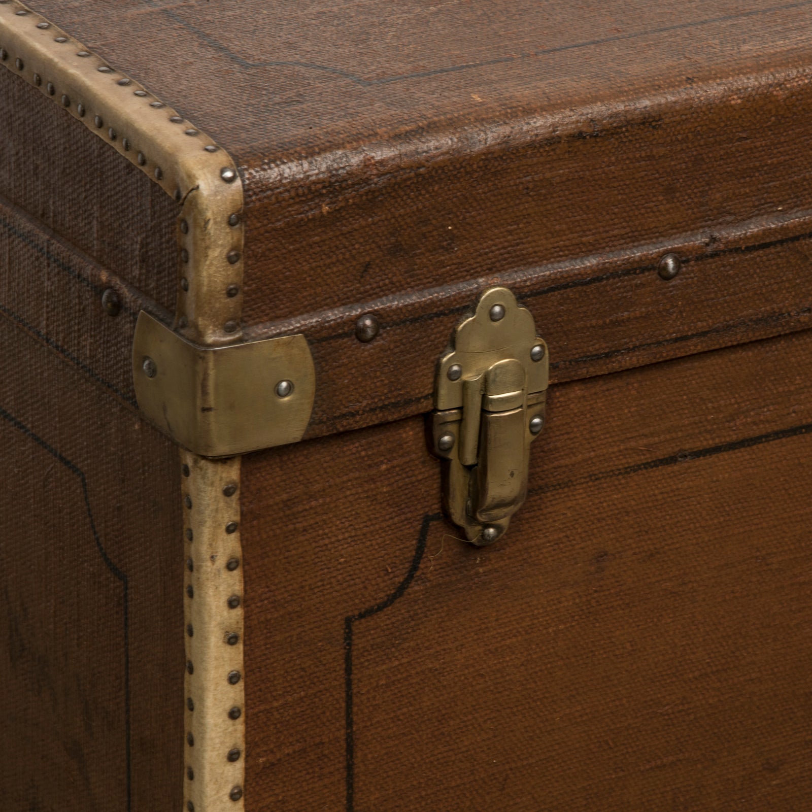 Close-up of a brown vintage canvas cube-shaped trunk with metal and brass accents
