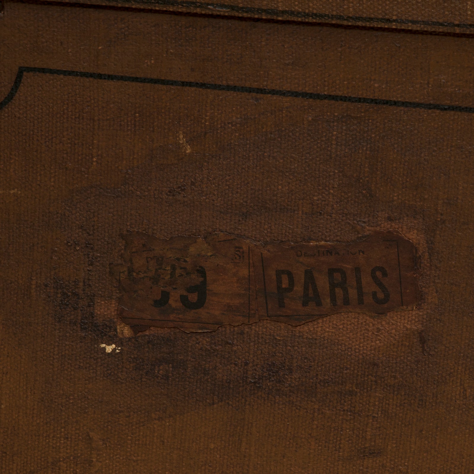 Close-up of a brown vintage canvas cube-shaped trunk with a vintage Paris label on the side