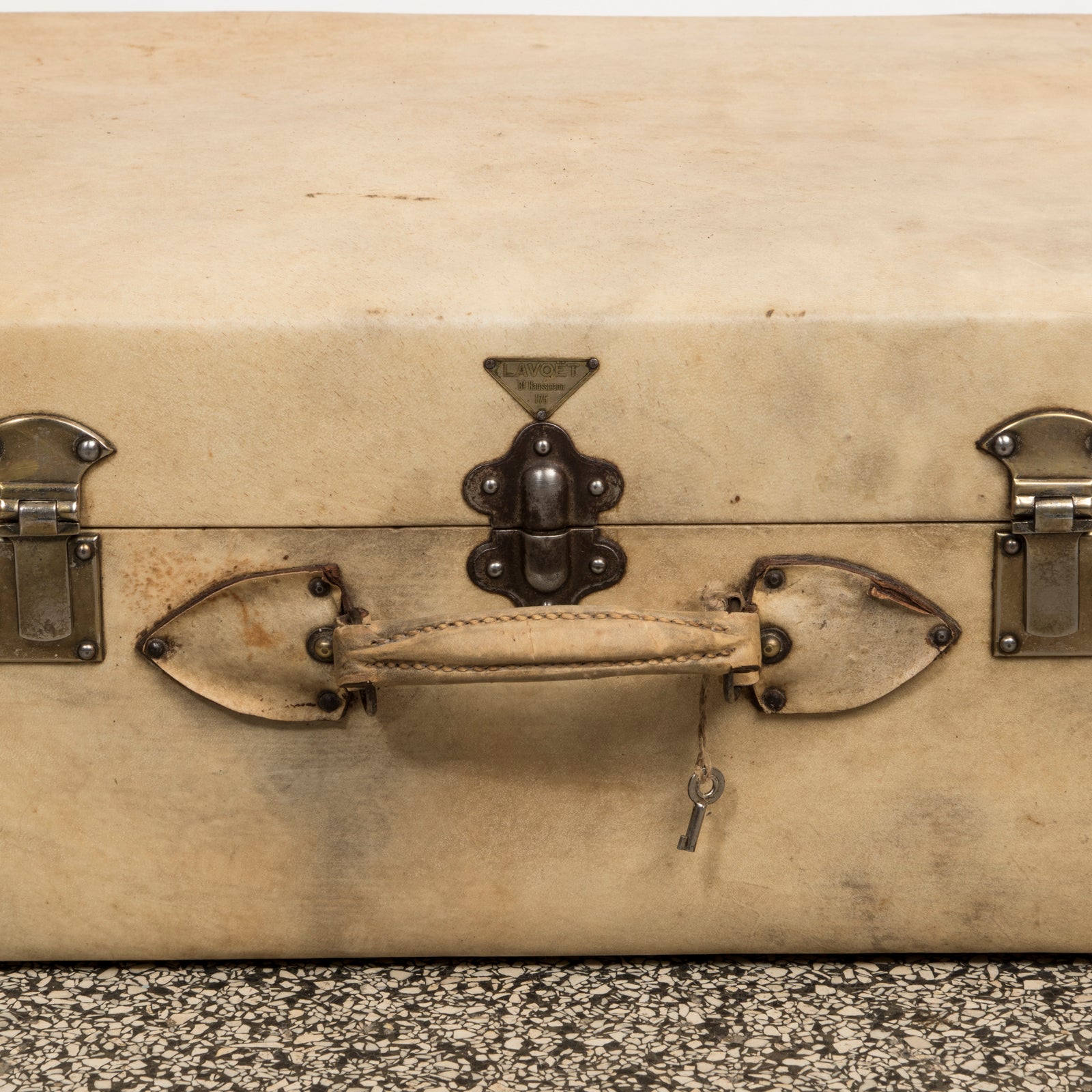 Close-up of the handle and brand name Lavoet of a vintage French cream leather suitcase with brass studs