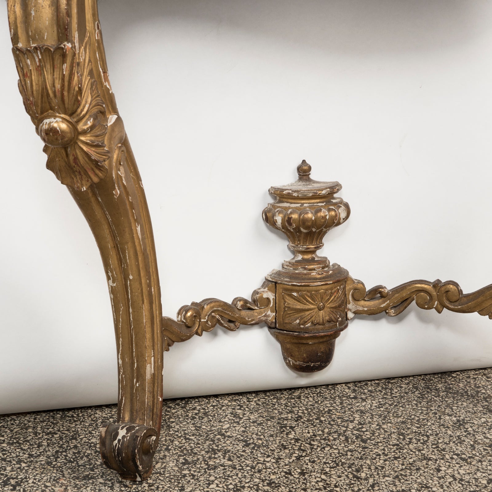 Close-up of a highly decorative antique French Louis XV style gilt wood console table with a white marble top, featuring intricate gilded designs and resting on carved legs. Showing some age appropriate wear and original patina.