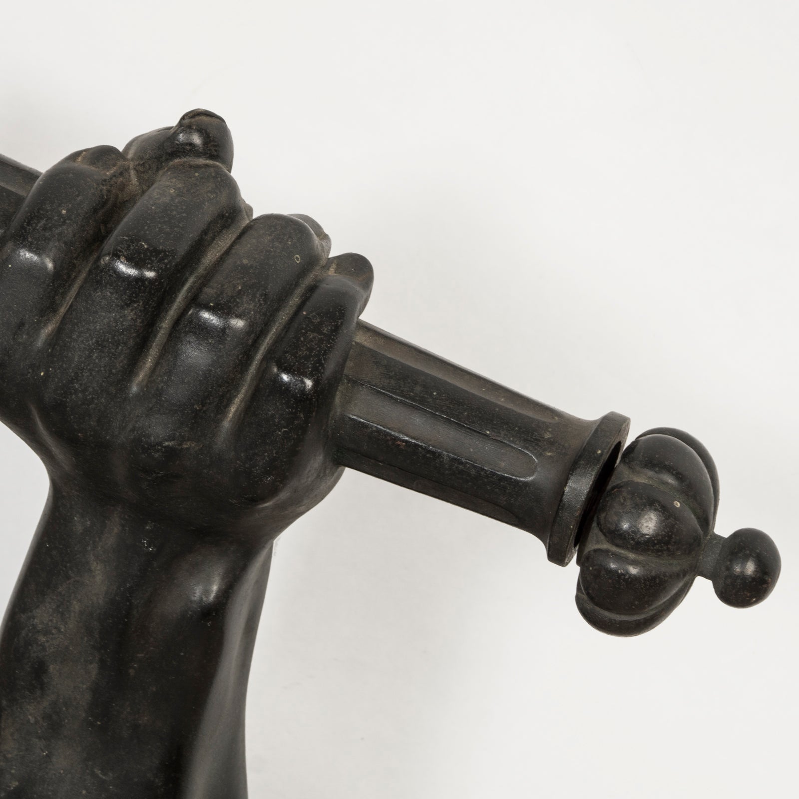 Close-up of a heavy antique French iron wall bracket, finely cast as an outstretched arm holding a torch, shown against a clean background.