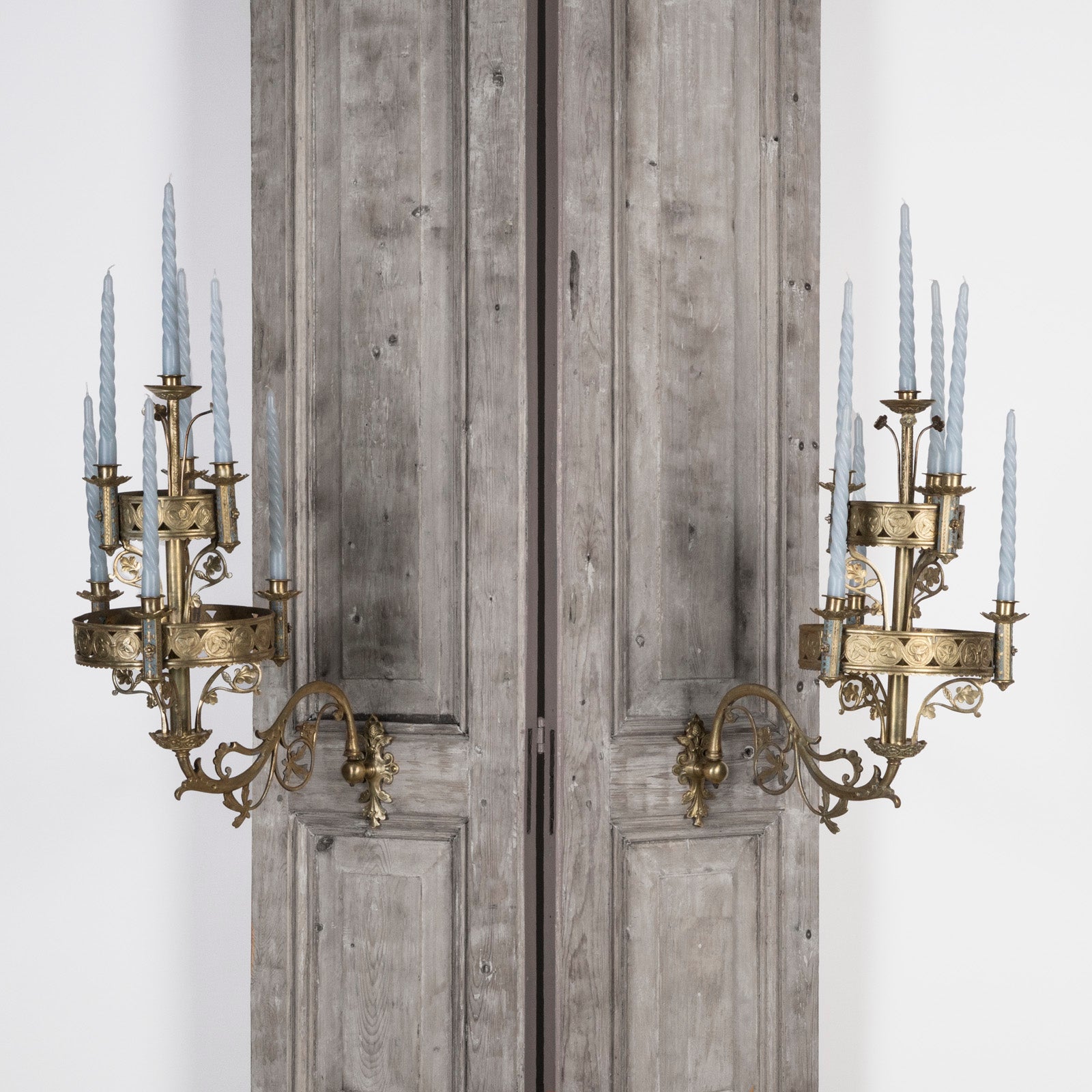 A pair of 19th century Gothic style candle sconces with gold-colored metal mountings and light blue swirl candles, designed for wall mounting, available at Wildschut Antiques