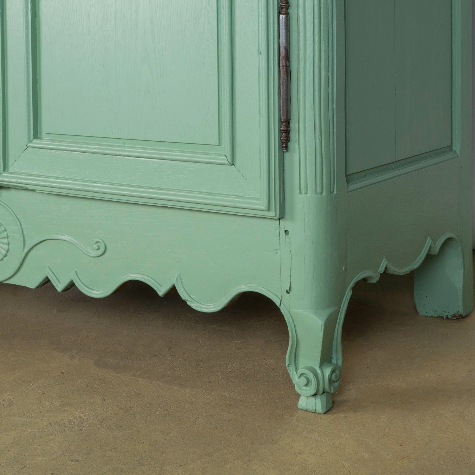 Close-up of the legs of a 19th-century green French marriage armoire with carved foliage motifs from Wildschut Antiques