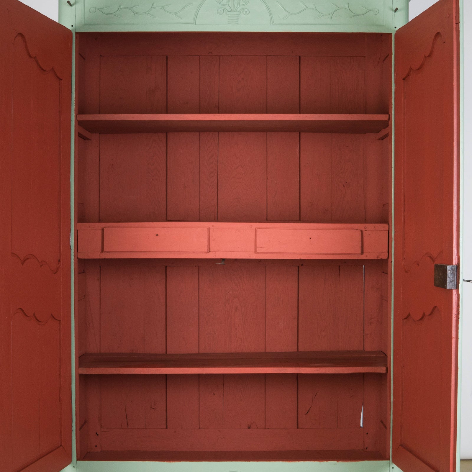 Red painted interior with shelves of an antique French armoire or wardrobe
