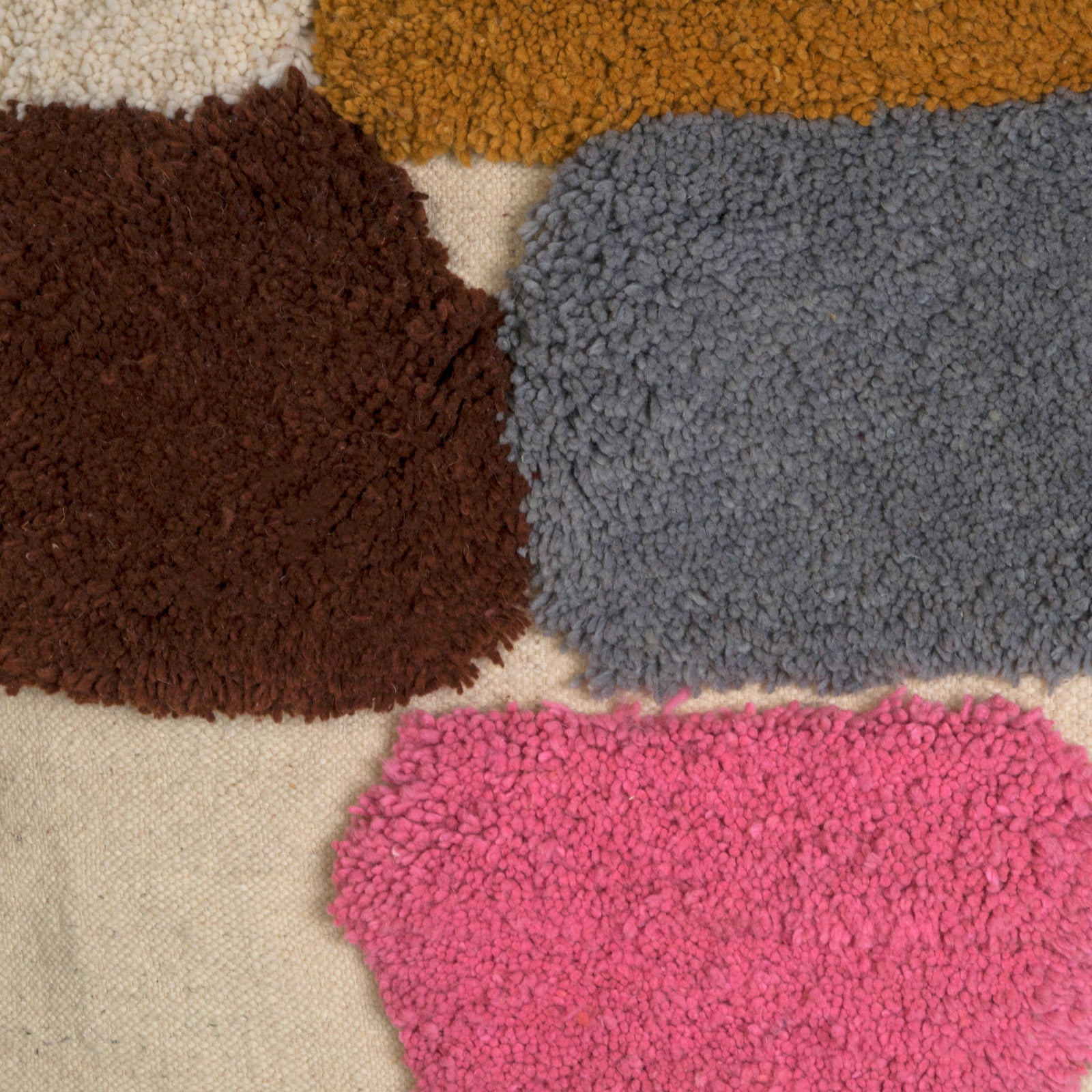 Close-up of a vintage 1970s Moroccan rug featuring an abstract composition of vibrant, irregularly shaped tufts in bold colors—such as cobalt blue, mustard yellow, fuchsia, burnt orange, and olive green—set against a natural cream background. The rug has a playful, textured appearance and is finished with fringed tassels on both ends.