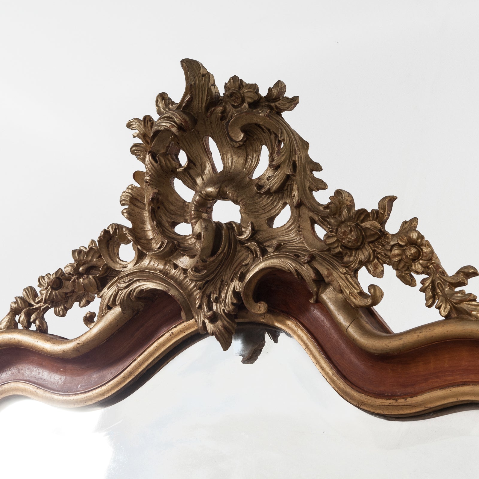 Close-up of the crest of a 19th century Italian Rococo style gilt wood mirror with floral decoration and a scalloped shell in the frame, available at Wildschut Antiques