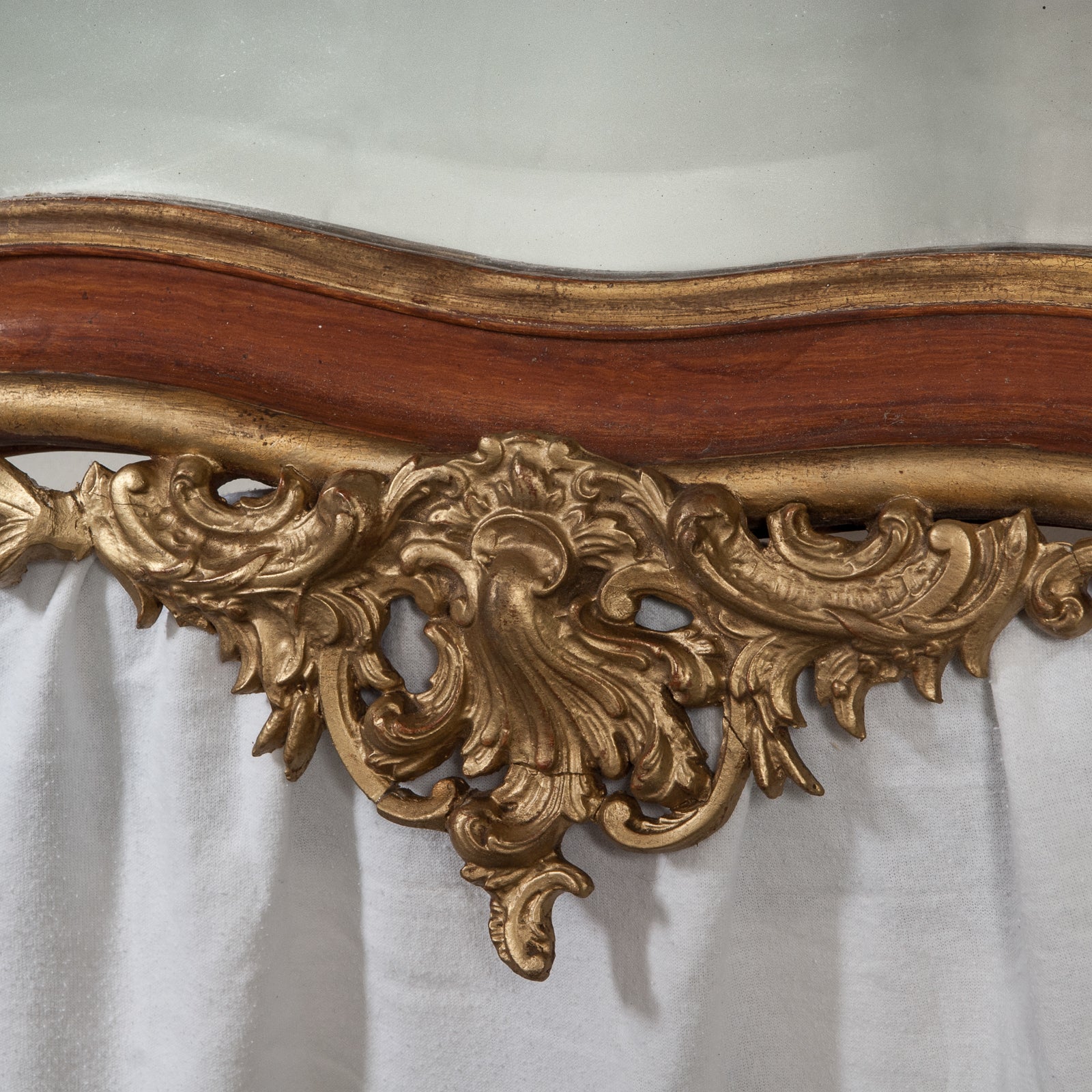 Close-up of the bottom part of a 19th century Italian Rococo style gilt wood mirror with floral decoration and a scalloped shell in the frame, available at Wildschut Antiques
