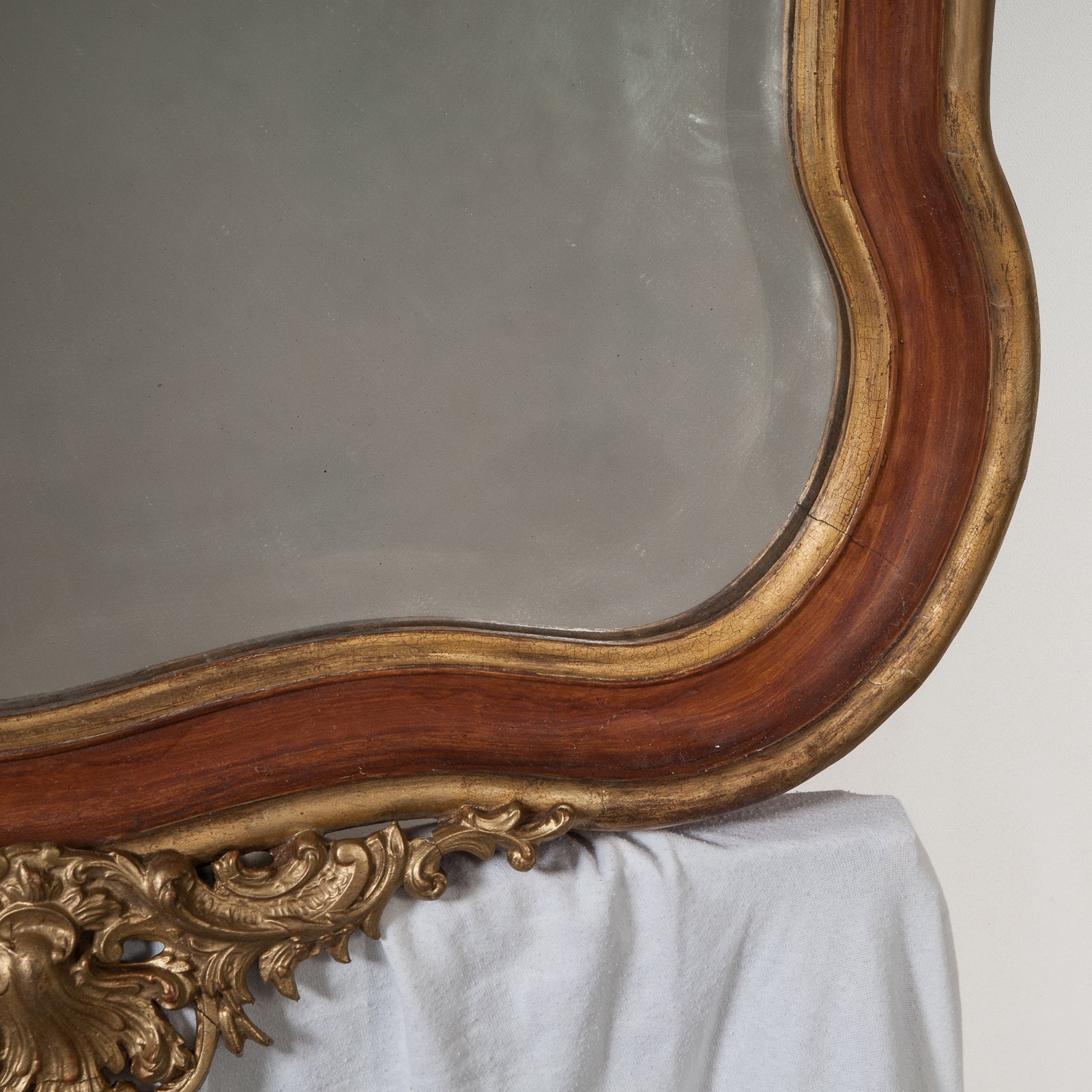 Close-up of a 19th century Italian Rococo style gilt wood mirror with floral decoration and a scalloped shell in the frame, available at Wildschut Antiques
