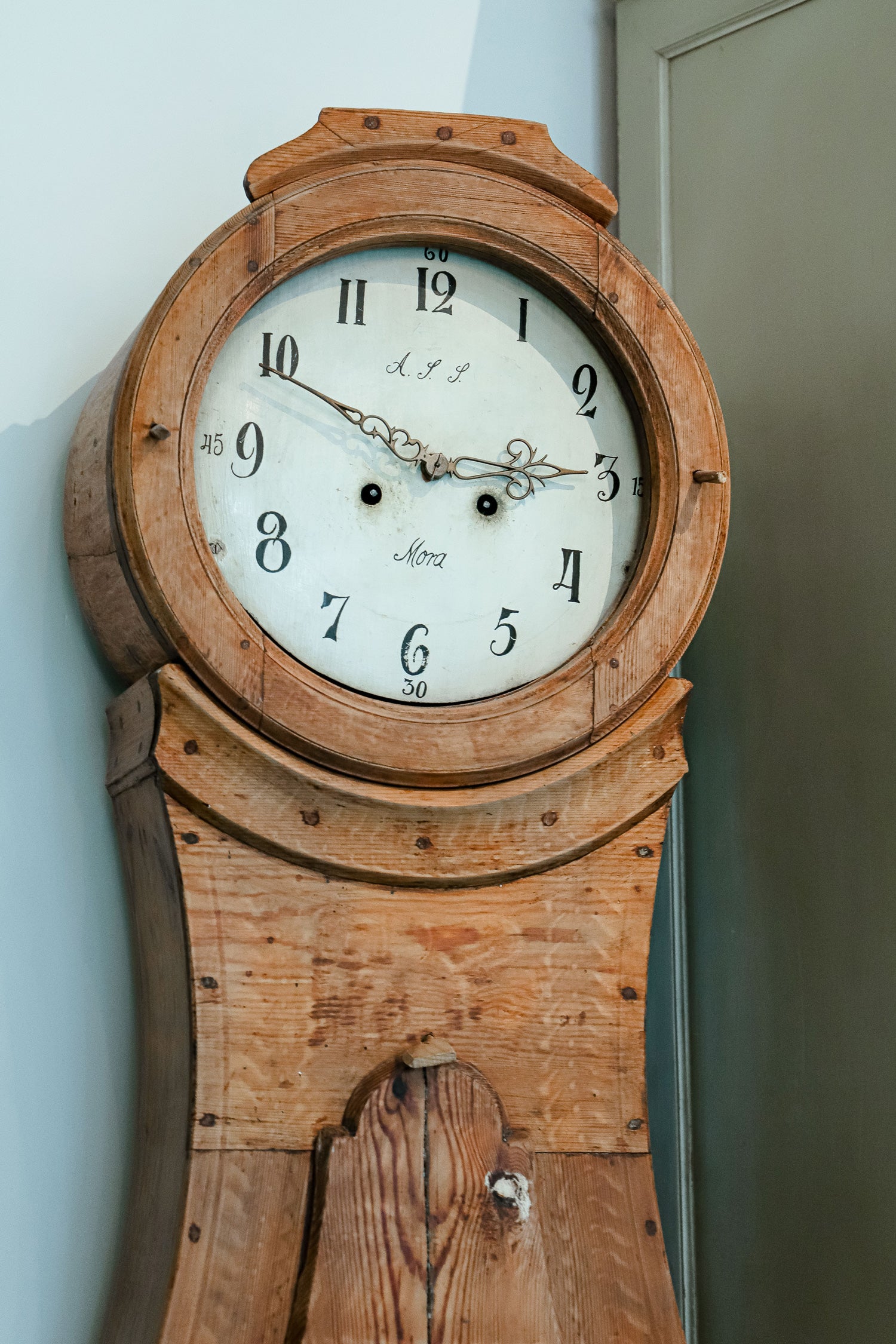 Close-up of an antique Swedish Mora clock with a natural finish, wide belly body, and a numeral face