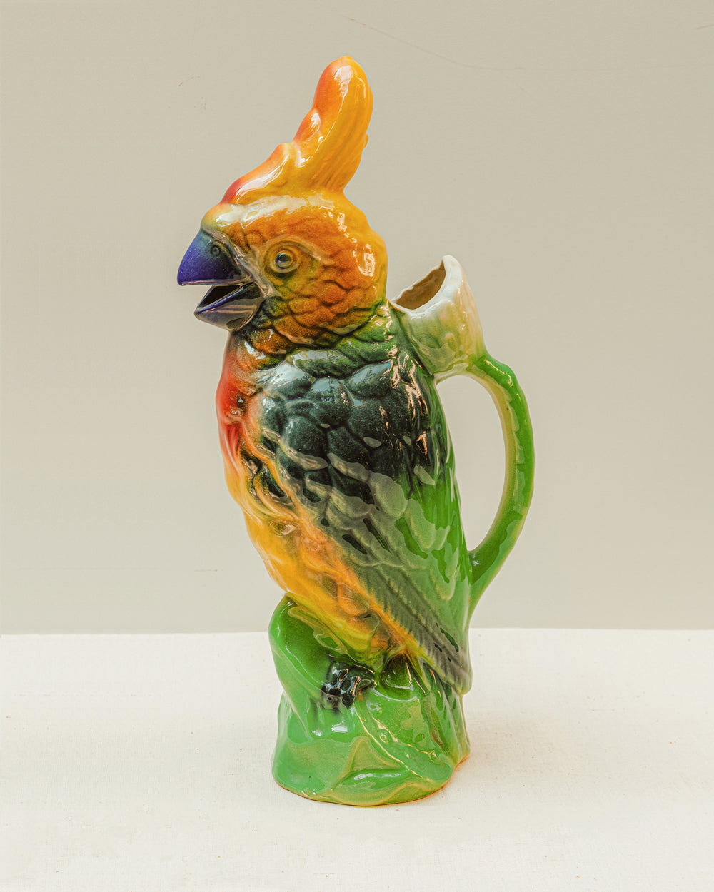 Ceramic parrot-shaped pitcher by St. Clement with colorful design on a white background, available via Wildschut Antiques