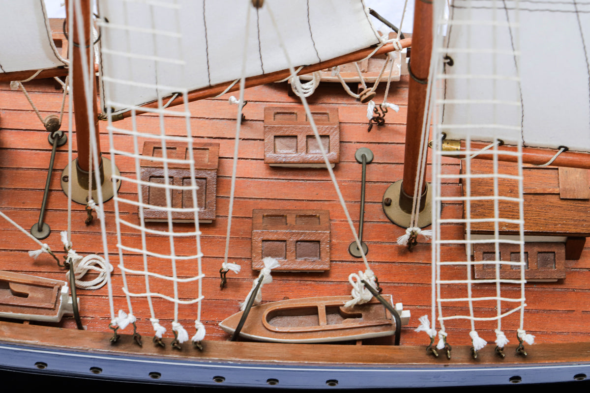 Close-up of a vintage Marco Polo sail boat model with a predominantly white sail and a brown wooden hull