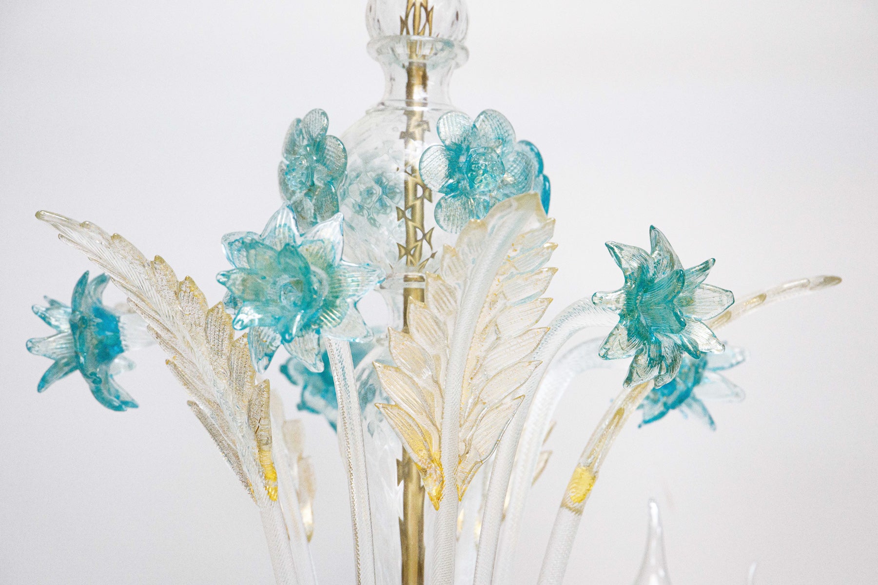 Close-up of the top of a Venetian Murano glass 6-light chandelier with white glass and blue and gold details, featuring intricate floral patterns
