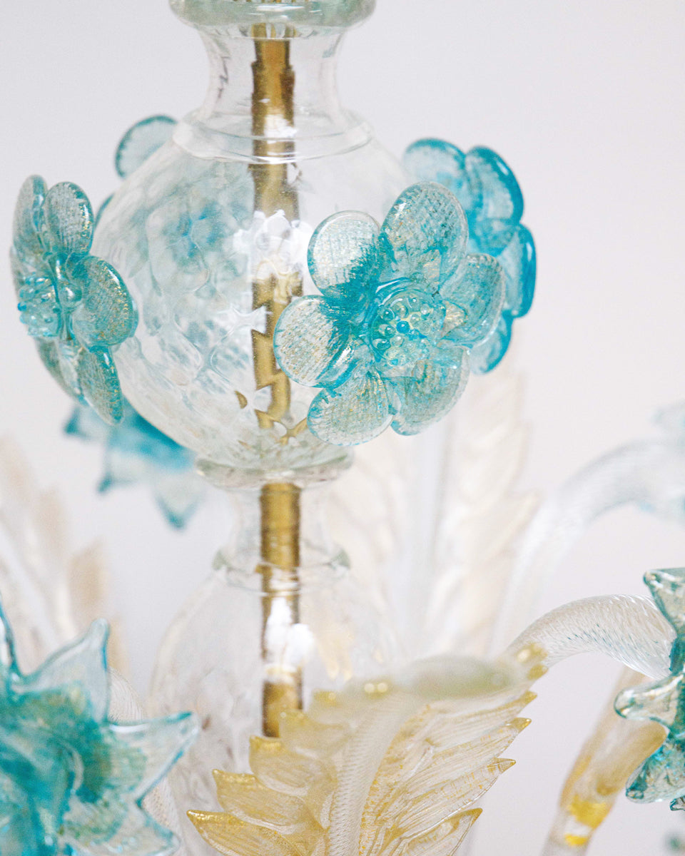 Close-up of a Venetian Murano glass 6-light chandelier with white glass and blue and gold details, featuring intricate floral patterns