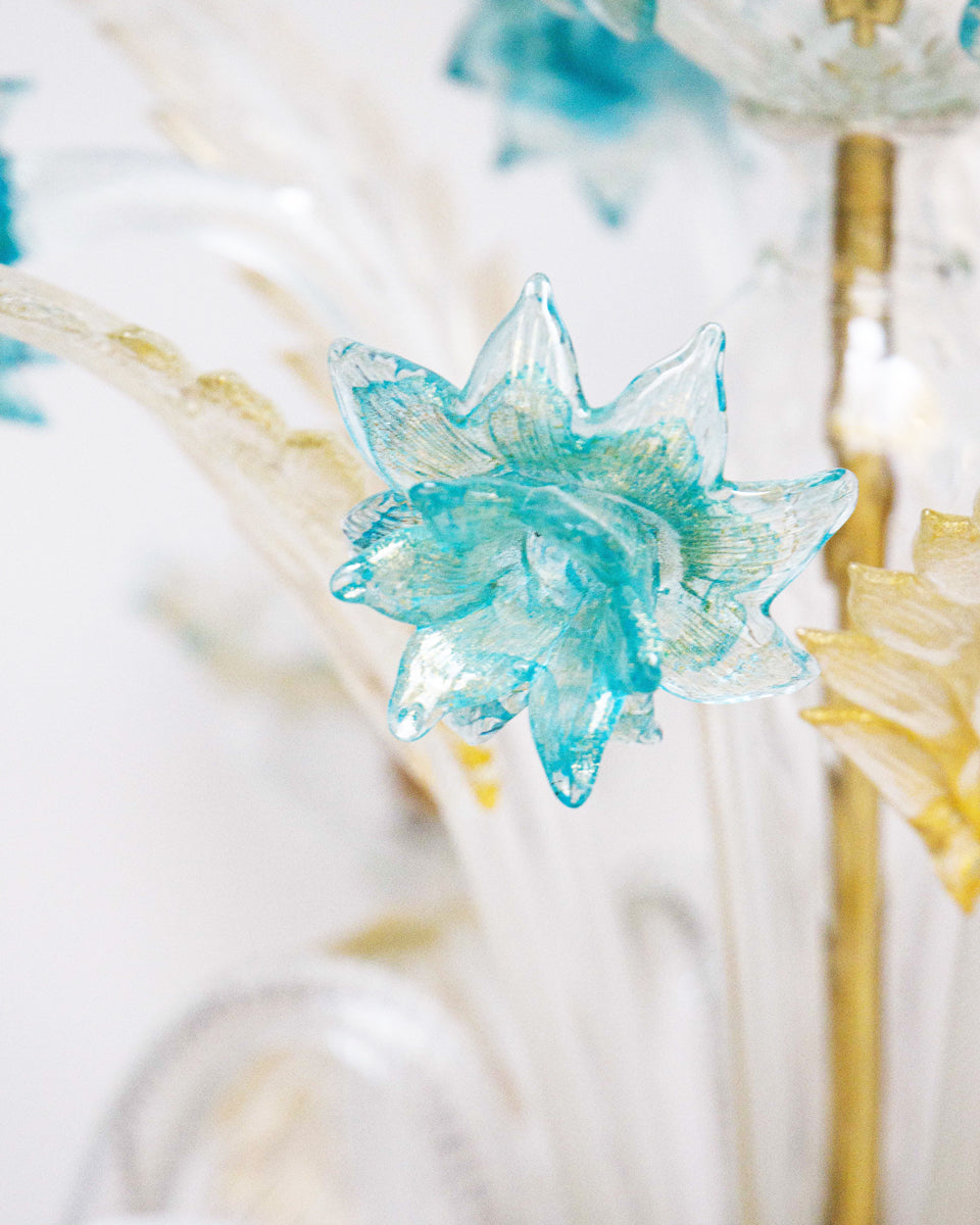 Close-up of a Venetian Murano glass 6-light chandelier with white glass and blue and gold details, featuring intricate floral patterns