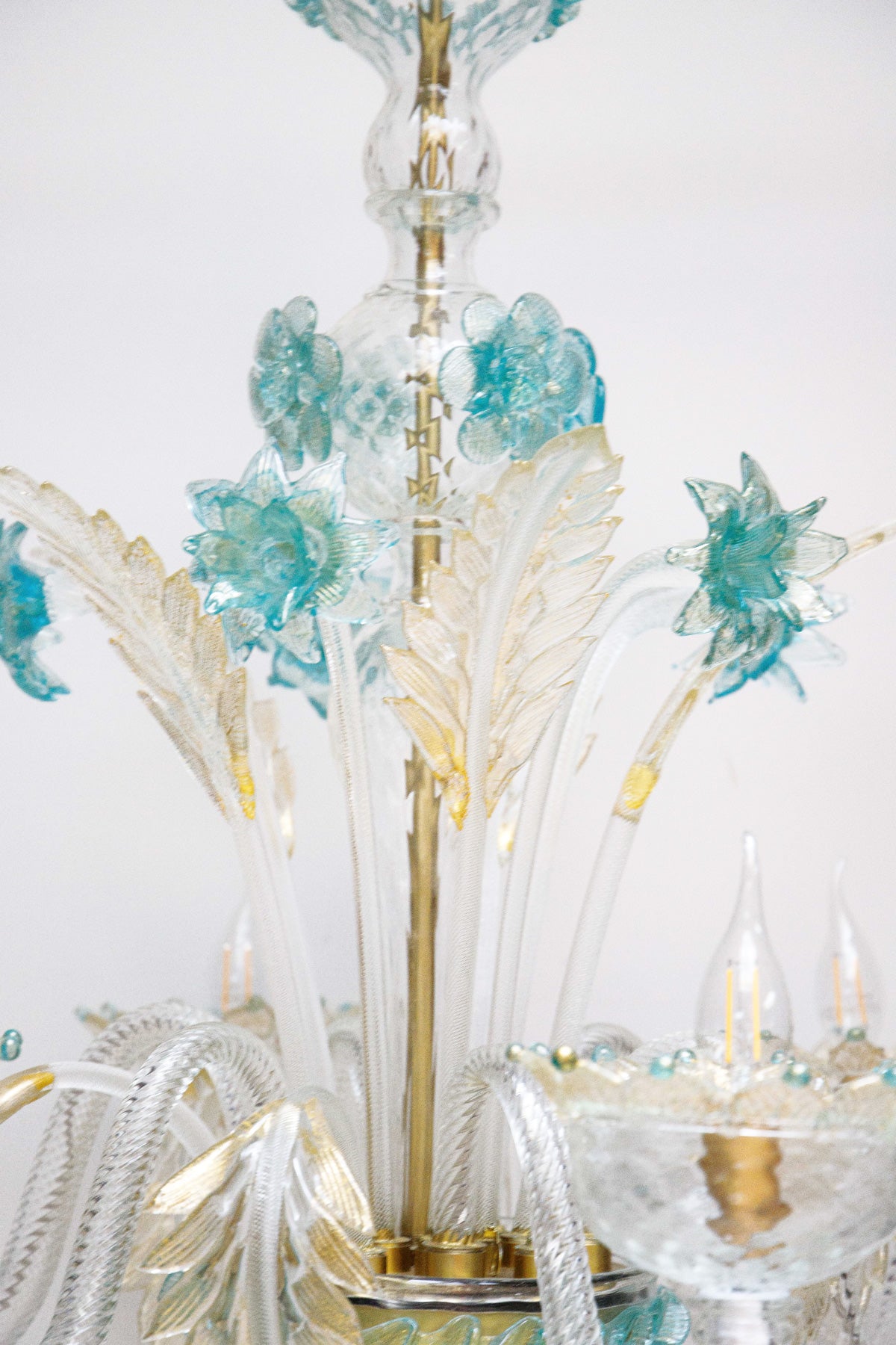 Close-up of a Venetian Murano glass 6-light chandelier with white glass and blue and gold details, featuring intricate floral patterns