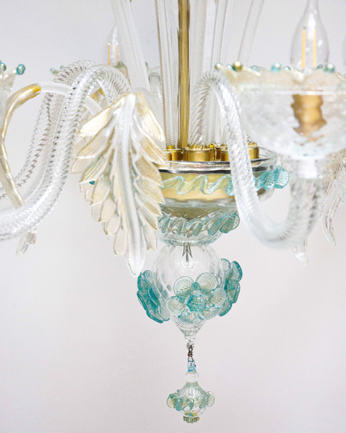 Close-up of a Venetian Murano glass 6-light chandelier with white glass and blue and gold details, featuring intricate floral patterns