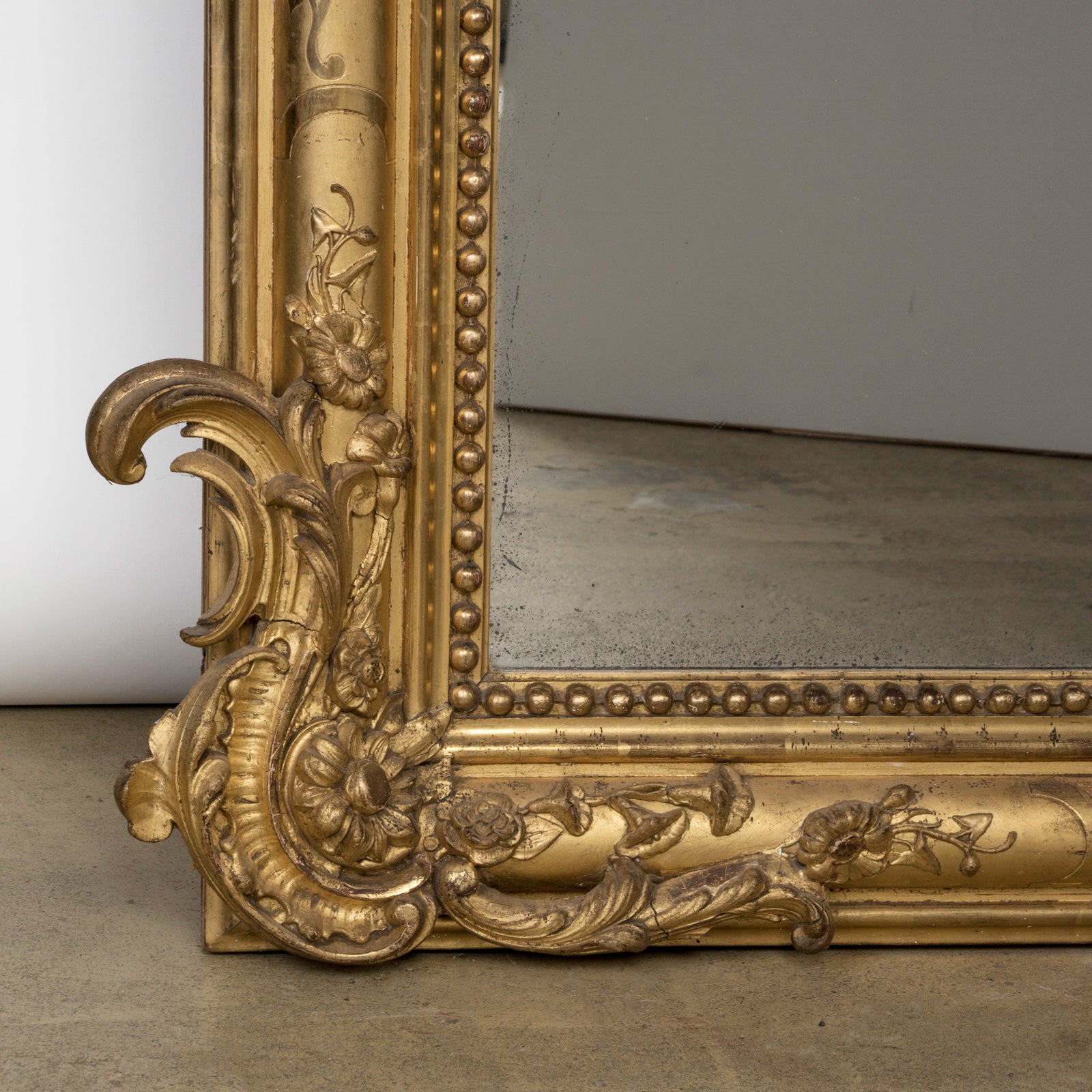 Close-up of a large Antique French 19th Century gold gilt mirror with weighty leaf and flower ornaments in the frame, available at Wildschut Antiques