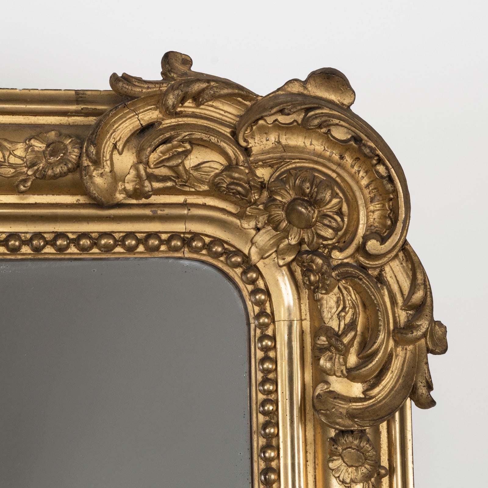 Close-up of a large Antique French 19th Century gold gilt mirror with weighty leaf and flower ornaments in the frame, available at Wildschut Antiques