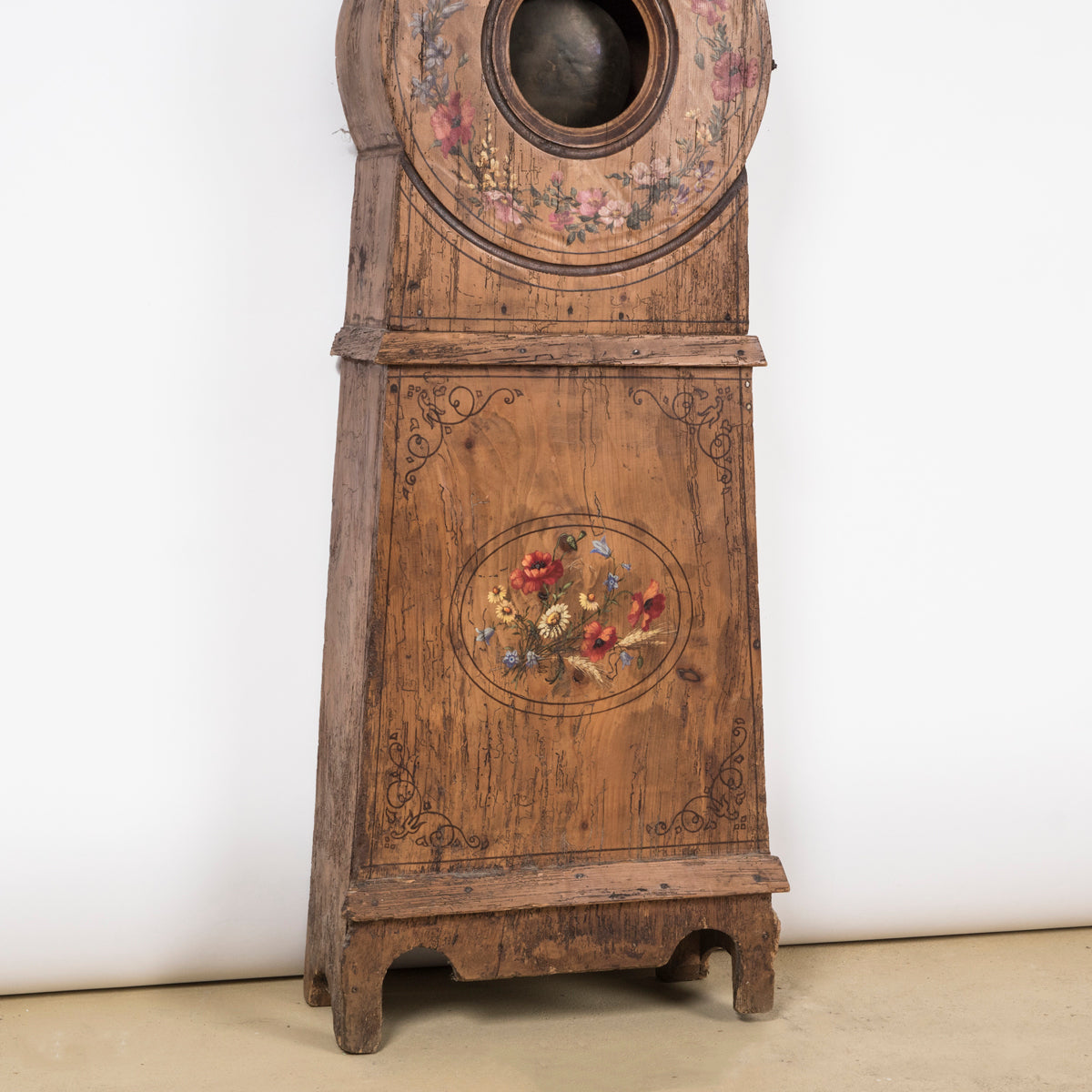 Close-up of the bottom part of a charming antique French tall case clock with a painted pine case decorated with floral motifs.