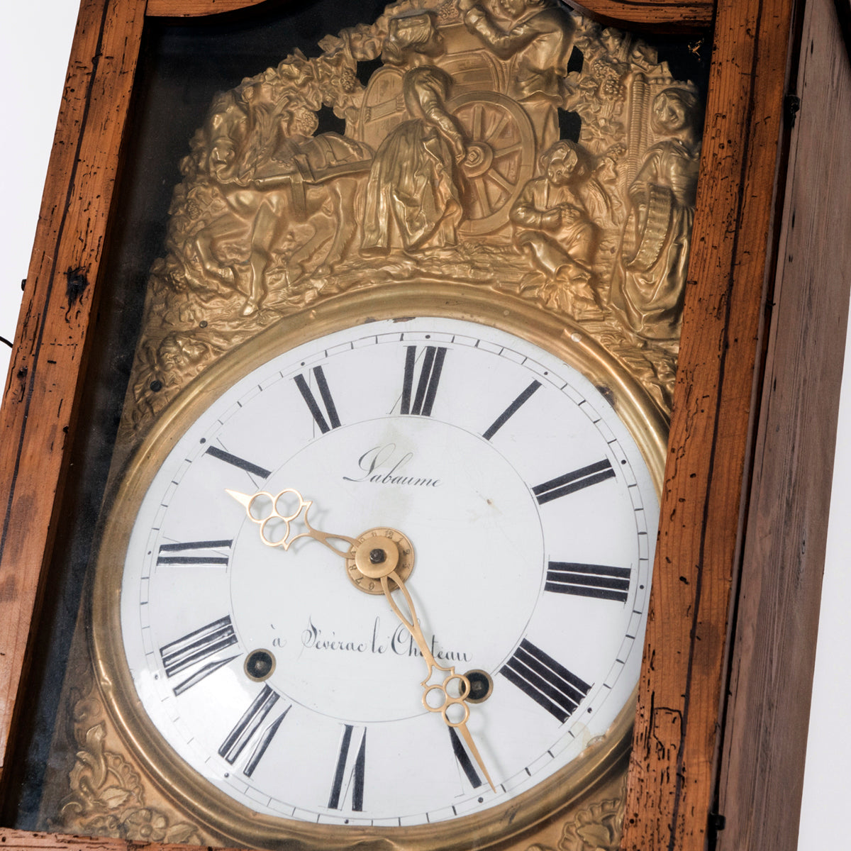 Close-up of an antique French tall case clock with a painted pine case decorated with floral motifs. The porcelain dial is signed “Labaume, à Sévérac-le-Château” and set in an embossed frame, dating circa 1870.