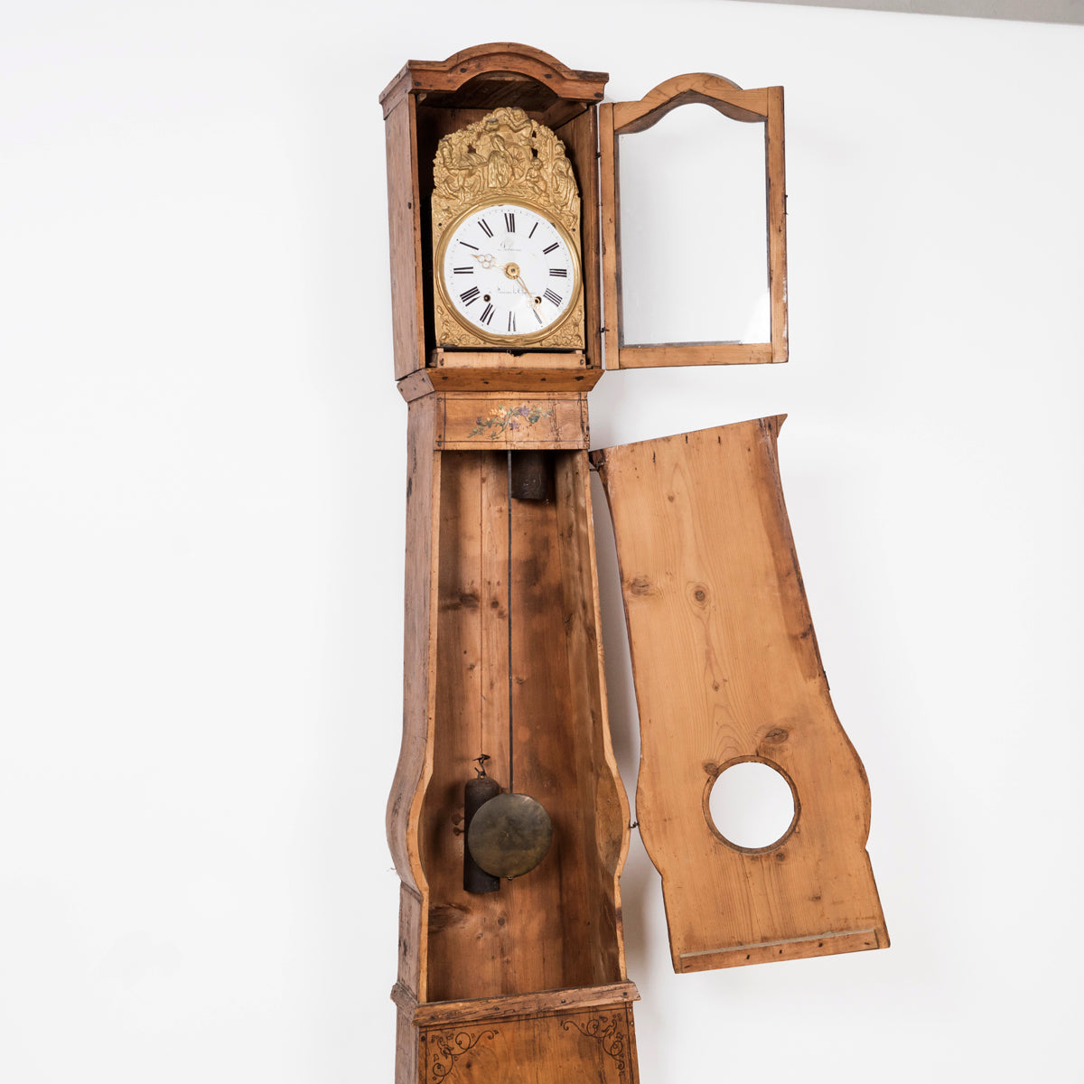 Close-up of a charming antique French tall case clock with a painted pine case decorated with floral motifs