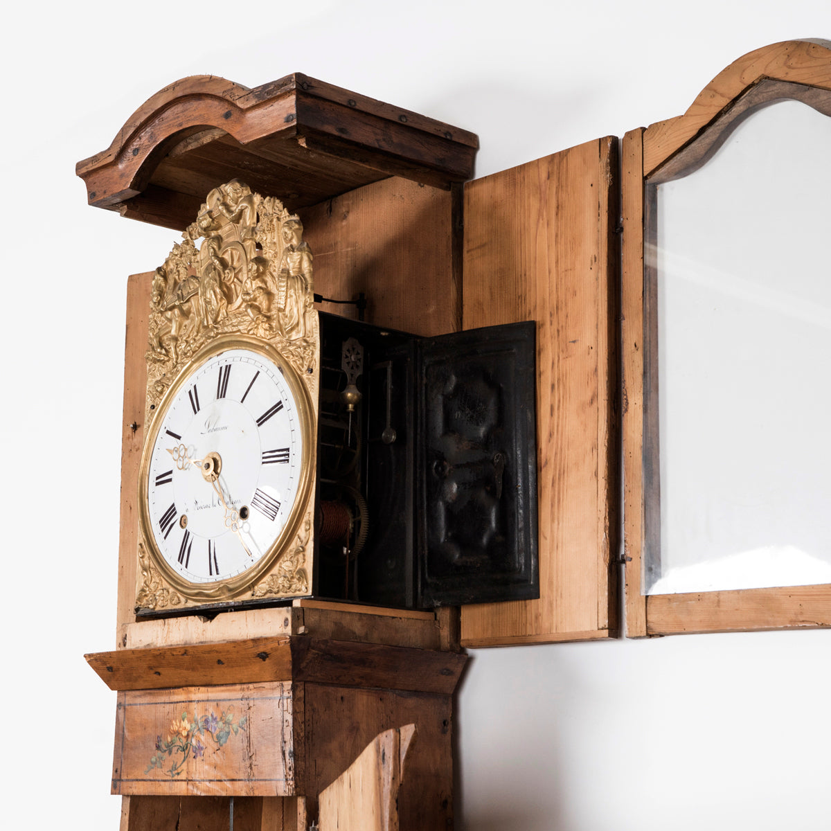 Close-up of a charming antique French tall case clock with a painted pine case decorated with floral motifs
