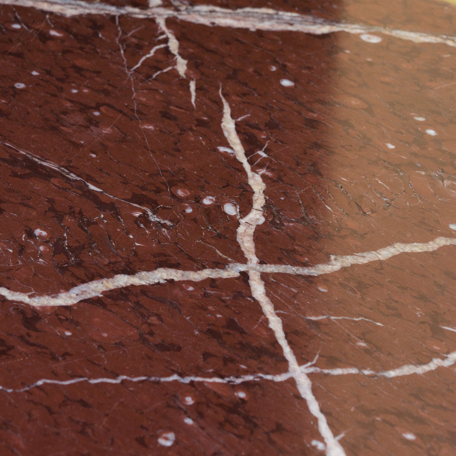 Close-up of a grand antique French Rococo Louis XV fireplace mantel, crafted from richly veined red-brown marble.