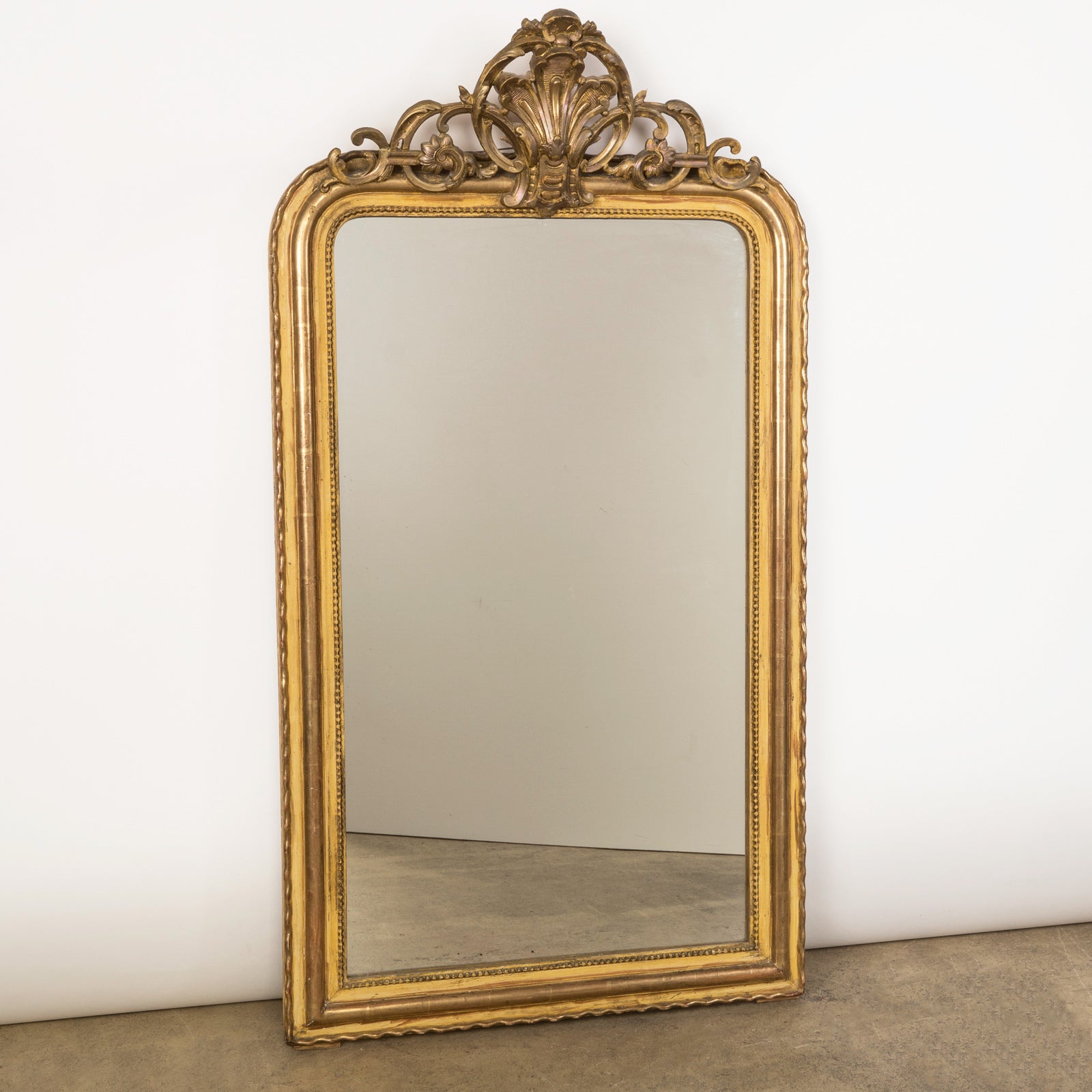 Antique 19th-century French Louis Philippe-style gilt mirror featuring a decorative crest and pearl beading along the inner perimeter. Available at Wildschut Antiques.