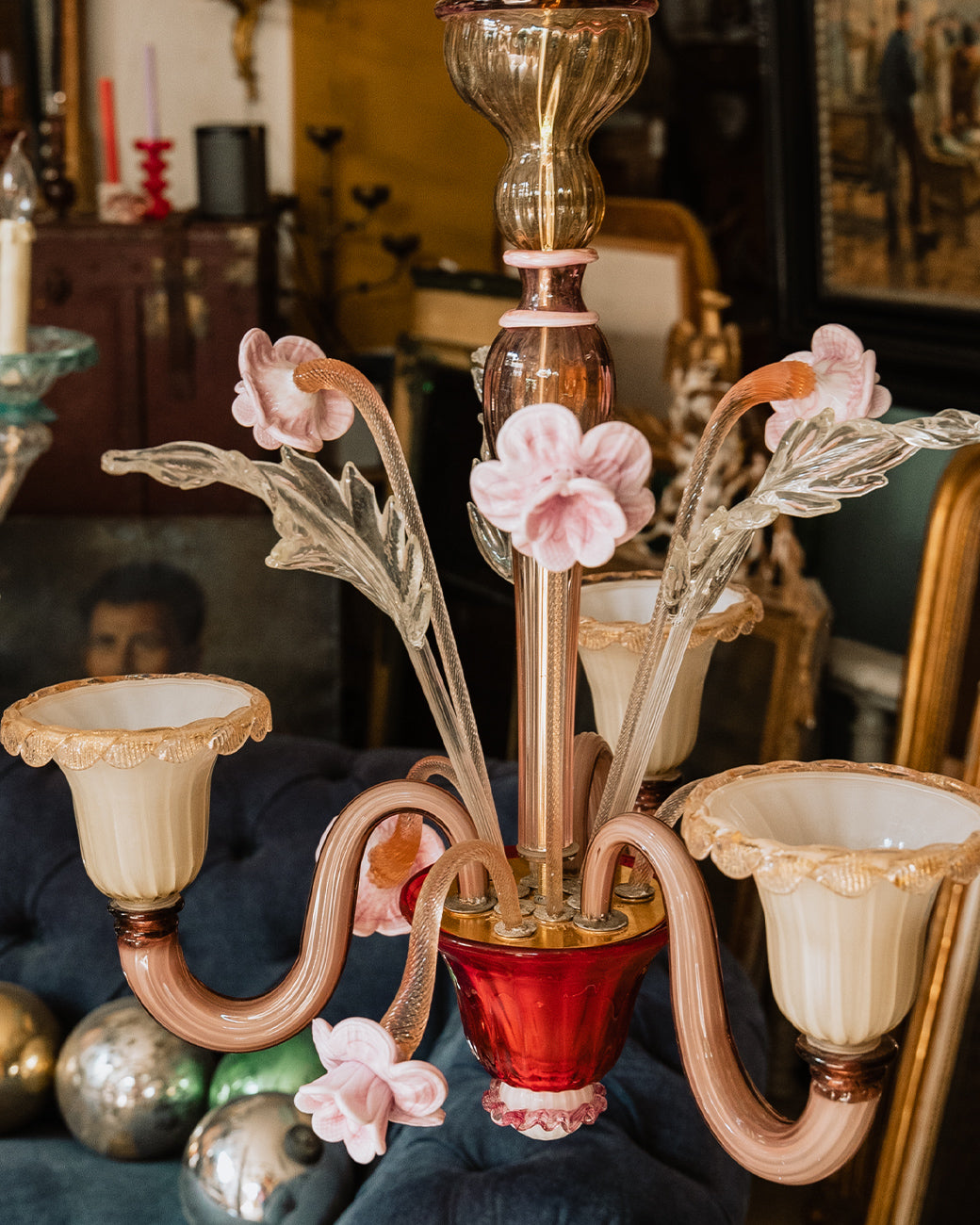 A small Venetian handblown Murano glass chandelier, in pink, white and red glass, featuring three lights and floral patterns, displayed in the store of Wildschut Antiques