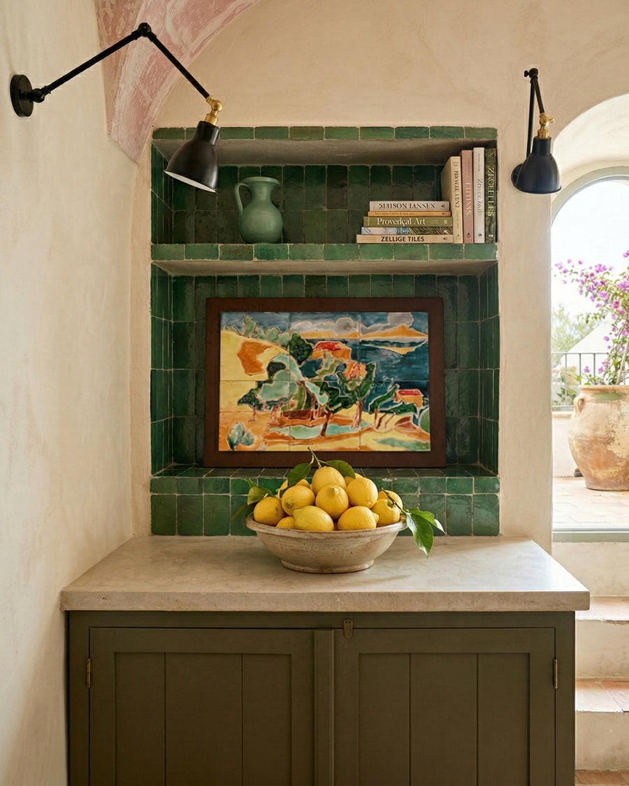 Kitchen counter with a bowl of lemons, green tiled wall, and framed artwork made up of tiles glaced in Anduze.