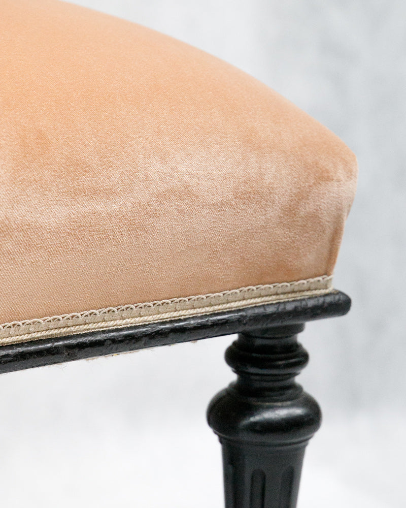 Close-up of a beige cushioned stool with black legs on a light gray background