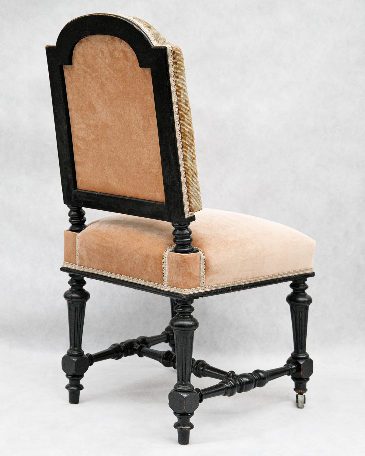 Decorative chair with salmon pink cushioned velvet seat and backrest on a white background