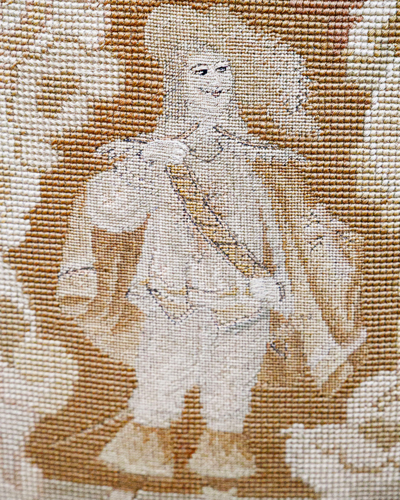 Embroidered portrait of a person in historical attire on fabric.