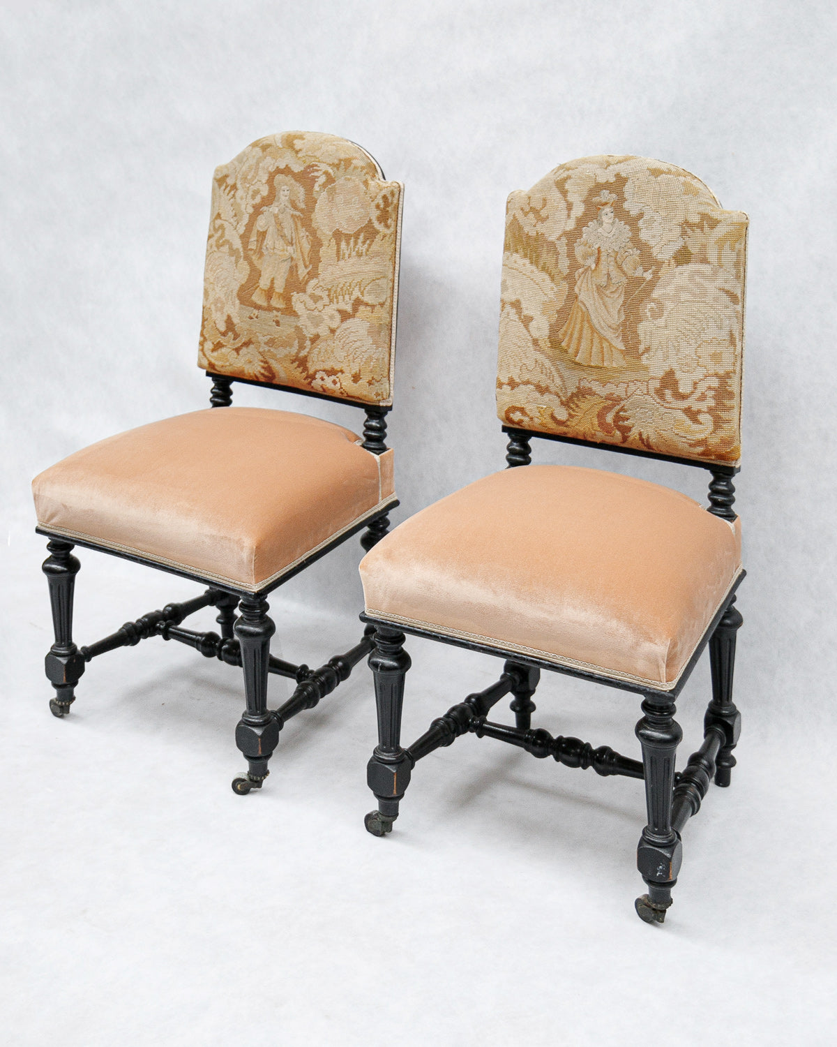 Pair of antique chairs with black carved wooden frames, pink velvet seats, and 17th-century style tapestry backs featuring a man and woman in period costume, available at Wildschut Antiques