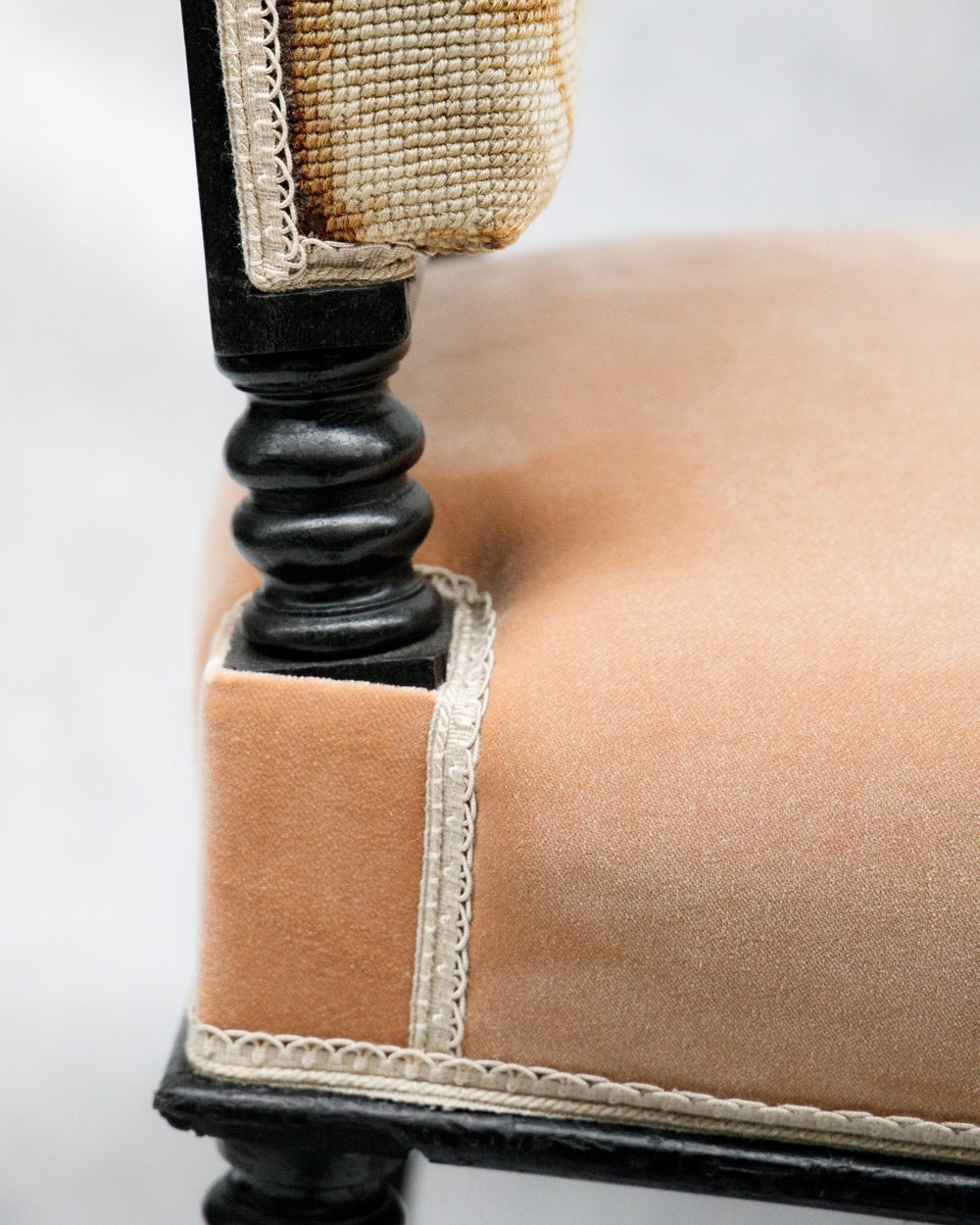 Close-up of a chair leg with a cushioned seat and wooden pink leg on a white background