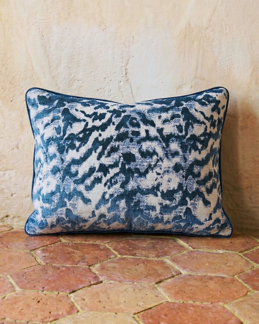 Decorative pillow with blue and white abstract pattern on a stone floor, available via Wildschut Antiques.