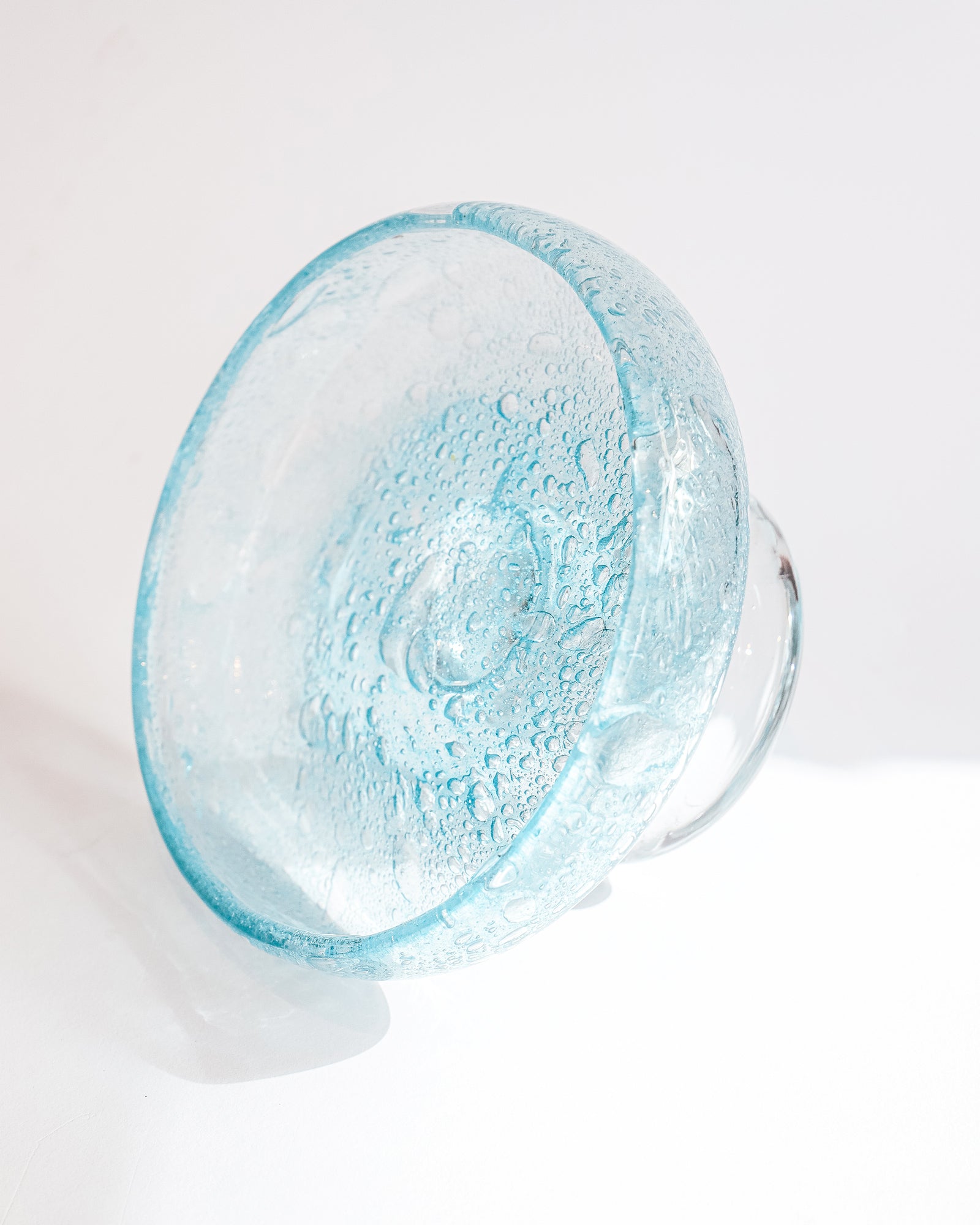 Side view of a vintage round blue glass fruit bowl resembling a heavy glass droplet, likely by Biot, France.