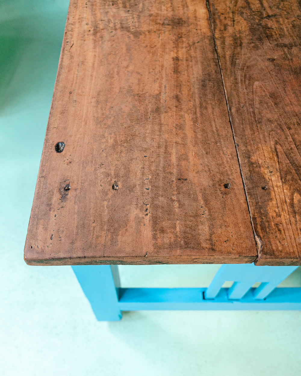 Close-up of a long vintage French wooden table with a blue painted base and a natural wood top
