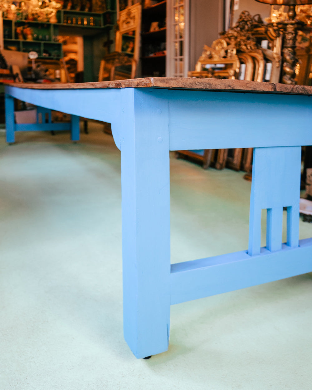 Close-up of a long vintage French wooden table with a blue painted base and a natural wood top, available at Wildschut Antiques