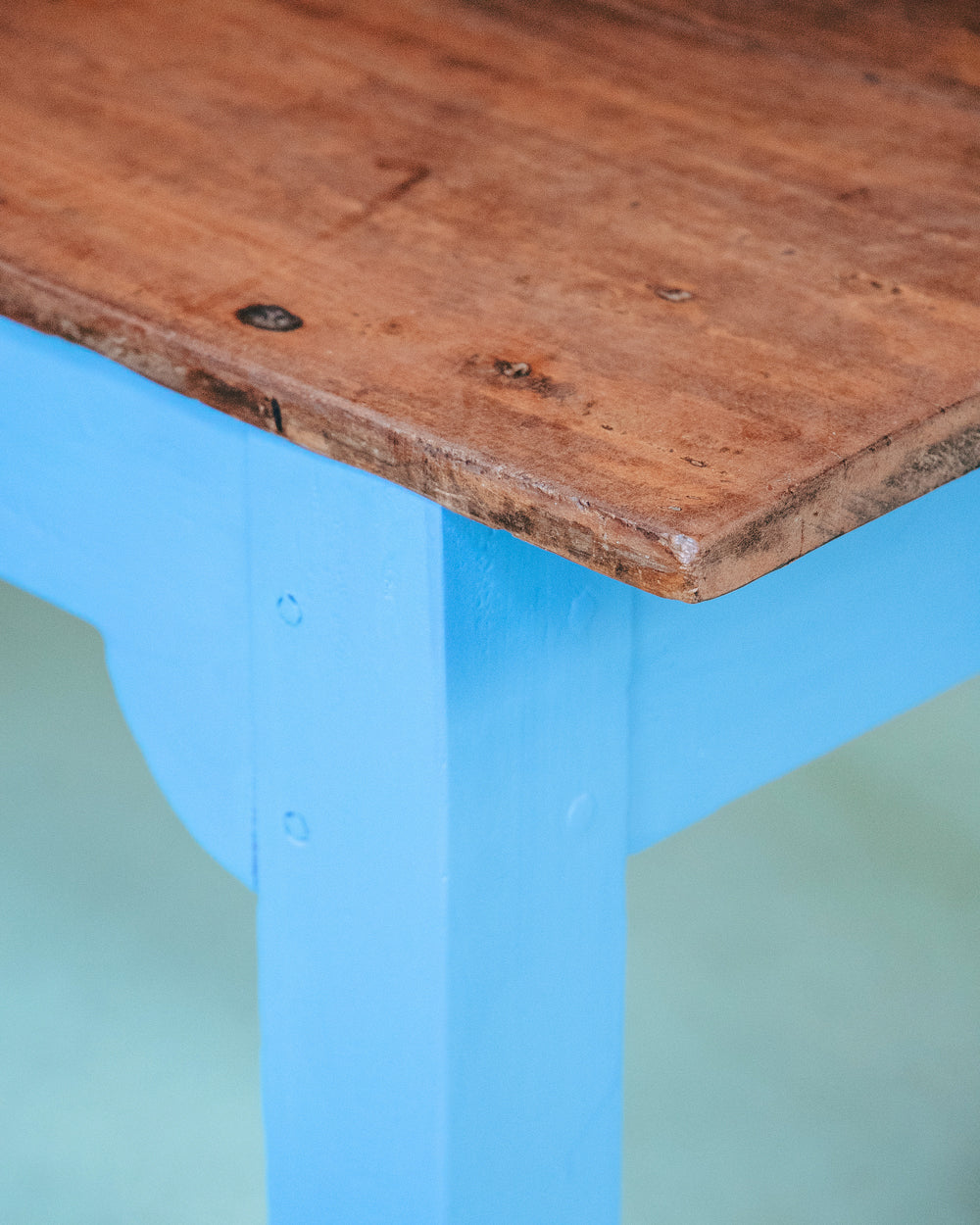 Close-up of a long vintage French wooden table with a blue painted base and a natural wood top