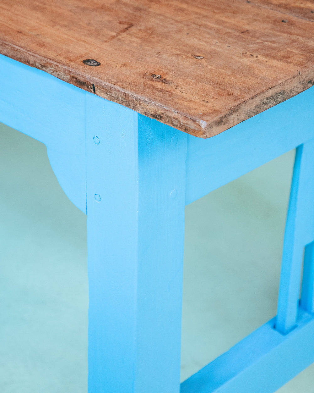 Close-up of a long vintage French wooden table with a blue painted base and a natural wood top