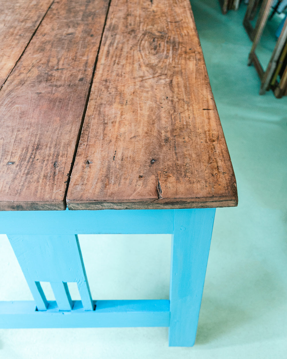 Close-up of a long vintage French wooden table with a blue painted base and a natural wood top