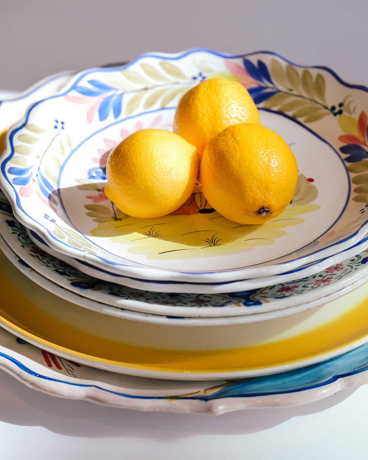 Assortment of vintage ceramic plates from France and Italy, styled with three yellow lemons