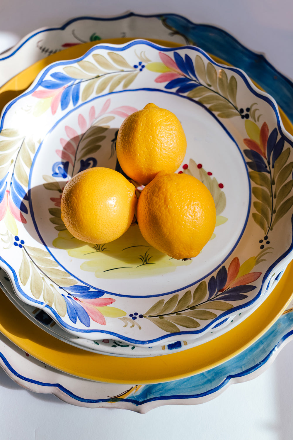 Assortment of vintage ceramic plates from France and Italy, styled with three yellow lemons