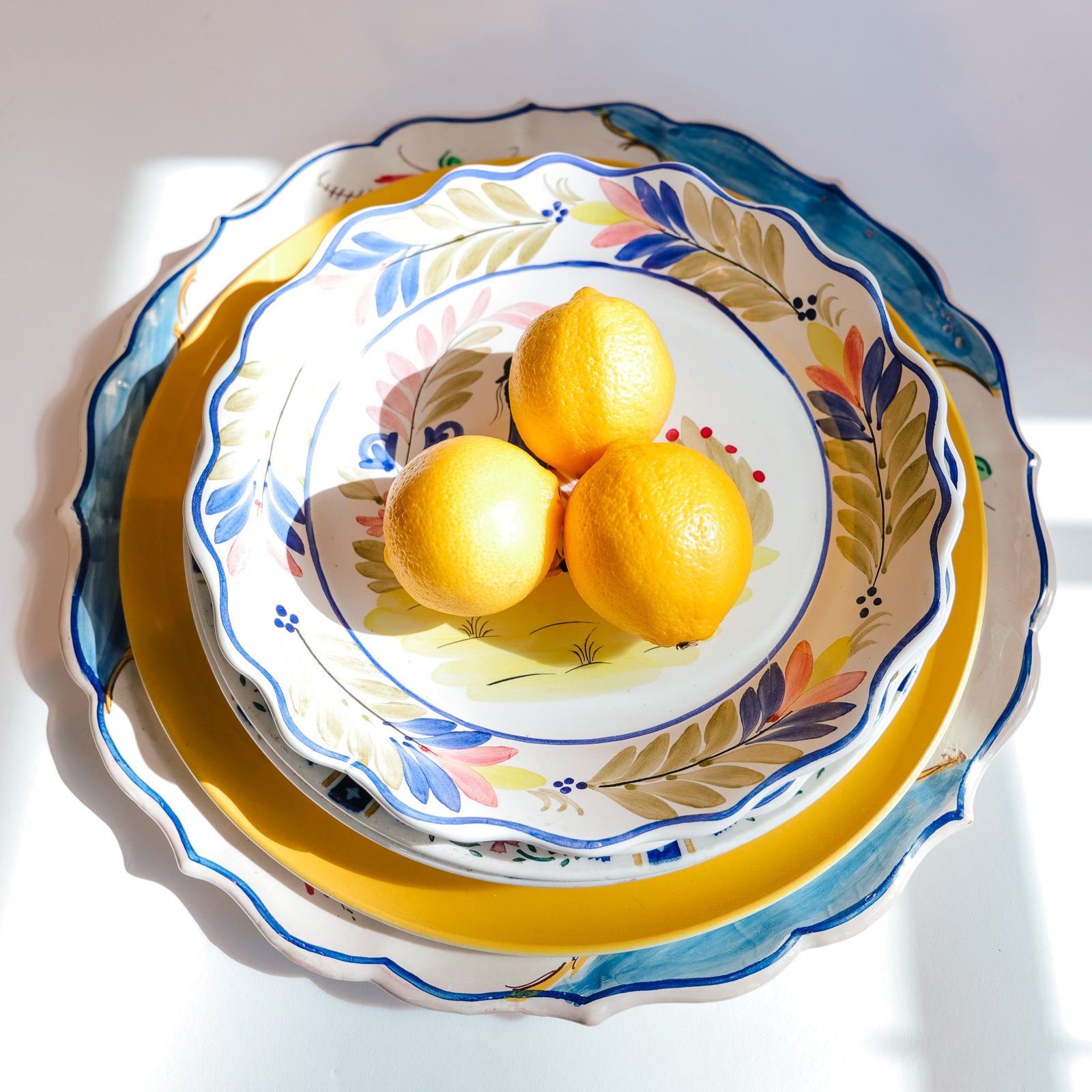 Assortment of vintage ceramic plates from France and Italy, styled with three yellow lemons